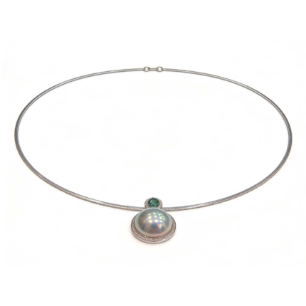 Luxury necklace featuring a large Amami pearl pendant with a green gemstone accent, set in a sleek Italian-crafted yellow gold and platinum collar, high-end jewelry